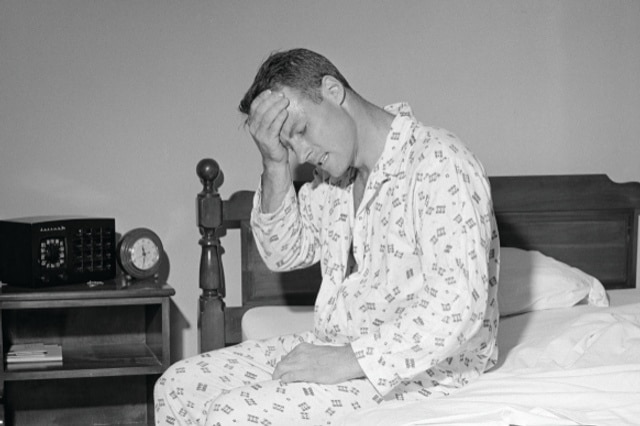 Black and White Picture of a man in bed hold his head